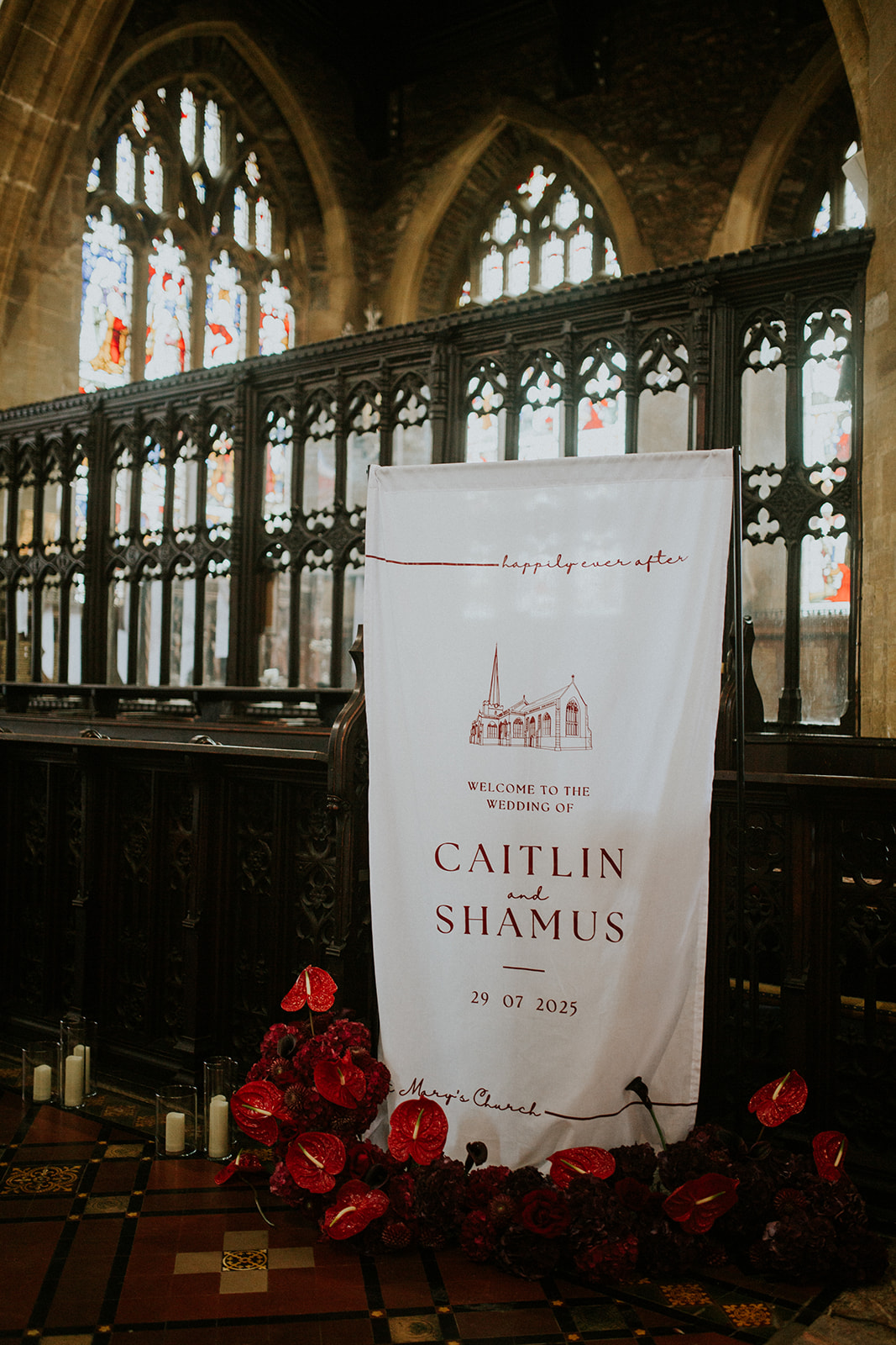 detail shot of fabric wedding welcome sign inside a church. Anthurium and candles are displayed on the floor