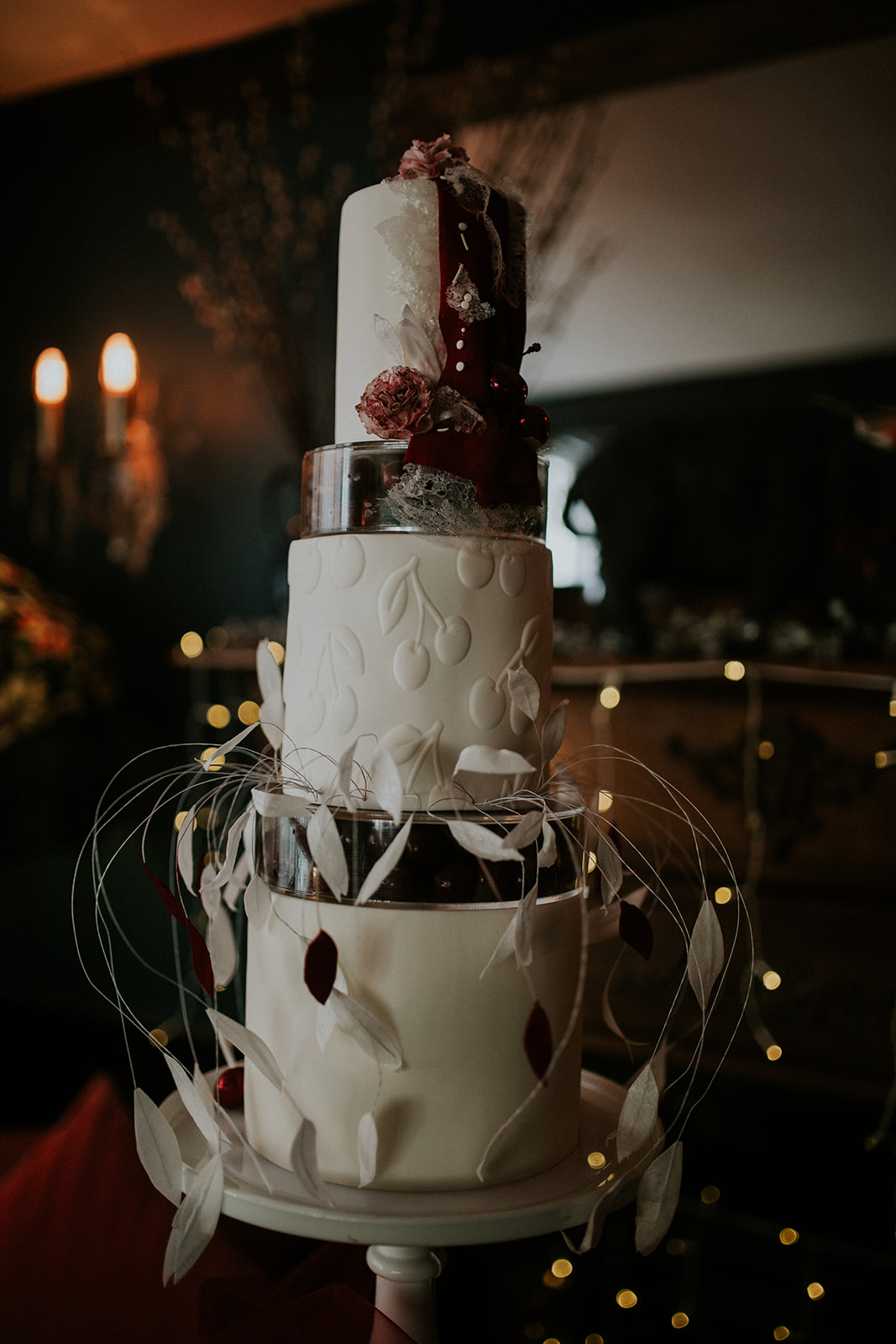 detail shot of sculptural wedding cake with embossed cherries and dangling leaf structures