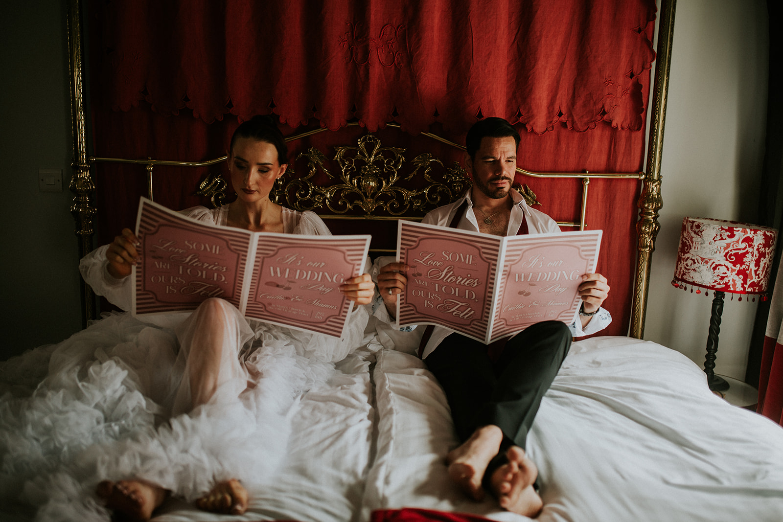 bride and groom sit in bed reading their personalised wedding newspapers