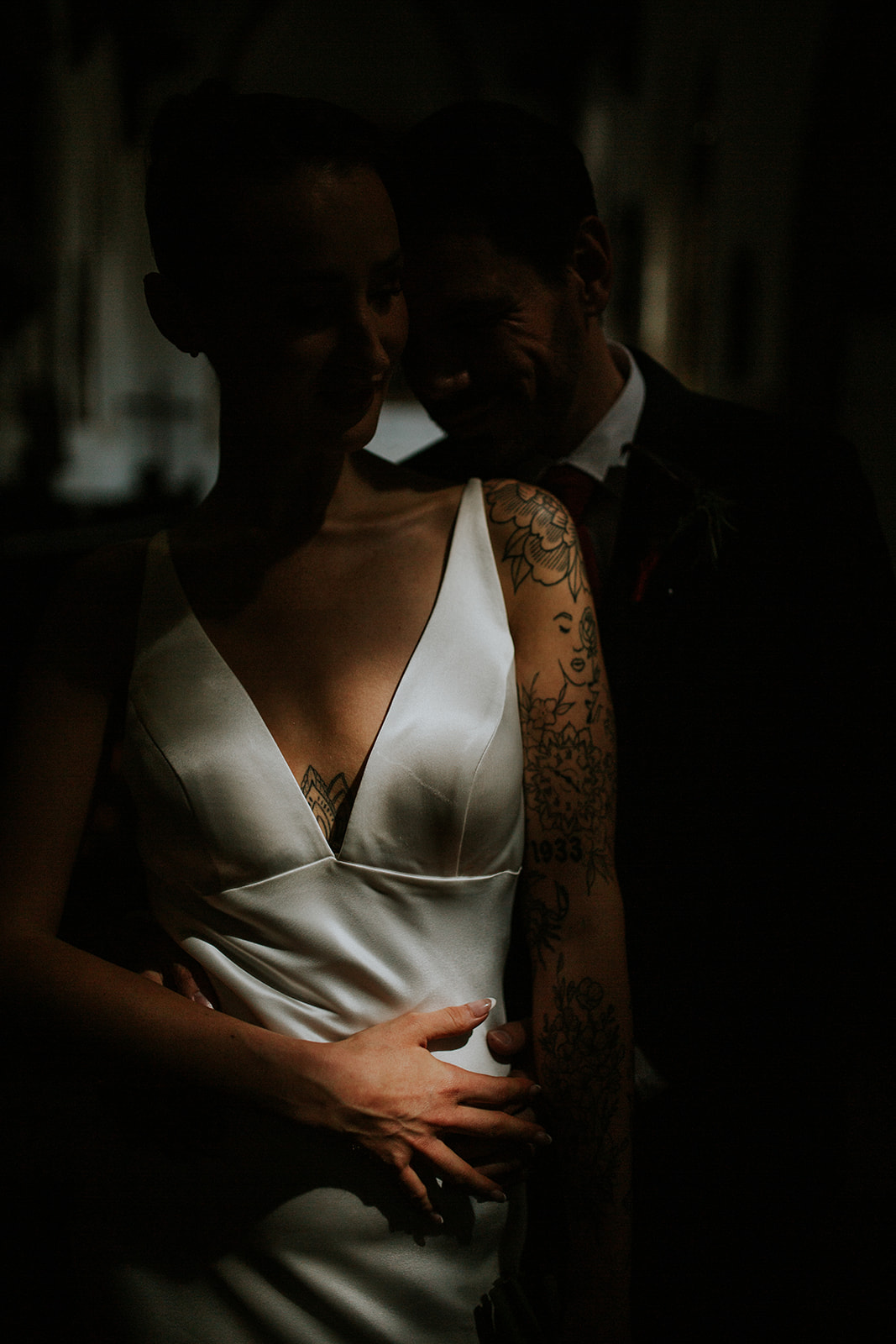 dark and moody atmospheric couple shot where only the bride's chest and torso is illuminated - the rest is in the shadow