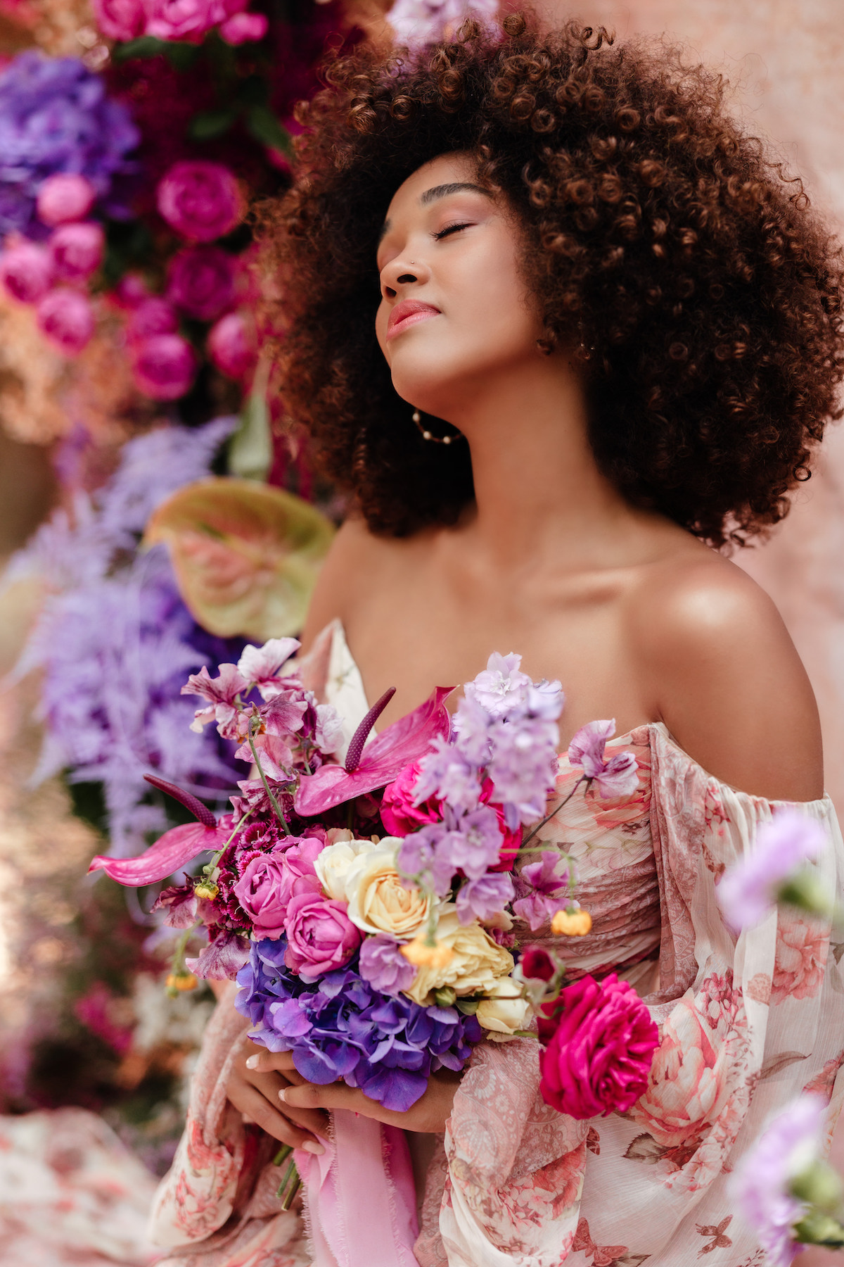 bride wearing floral wedding dress holding a bouquet of brightly coloured flowers