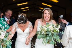 LGBTQ+ brides walking out of wedding ceremony holding hands - Eucalyptus wedding bouquet - LGBTQ+ bride