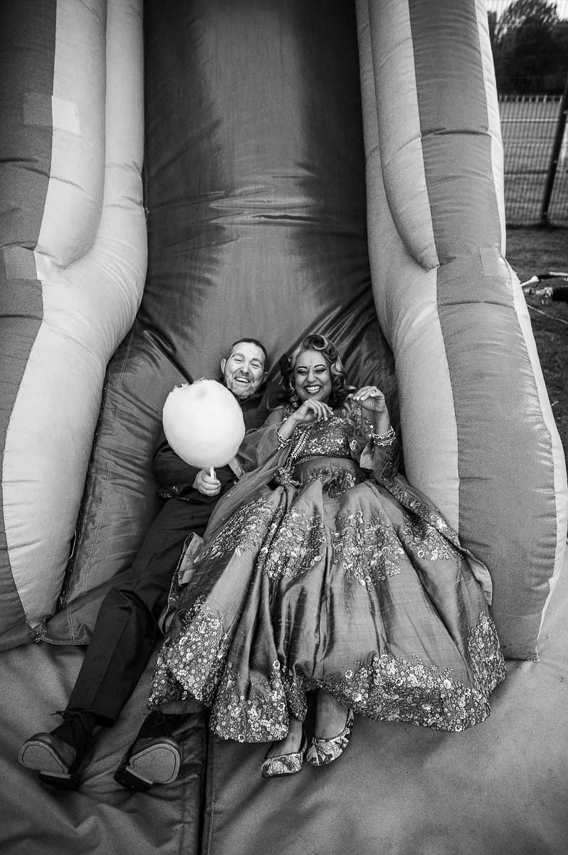 Bride and groom sliding down an inflatable slide as part of their cultural fusion wedding