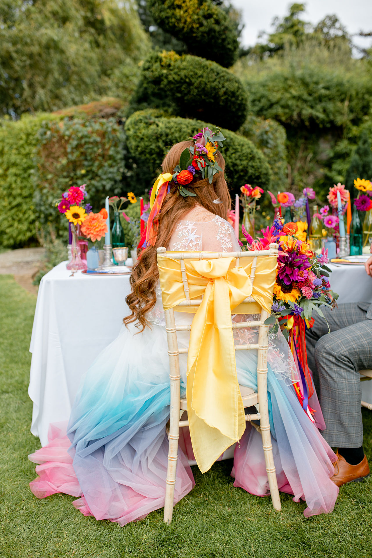 outdoor rainbow wedding - colourful wedding table - colourful chair covers - rainbow wedding flowers
