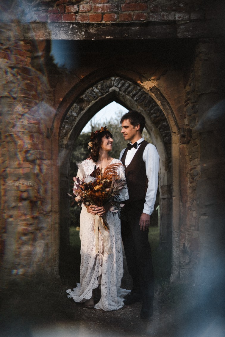 wedding elopement - autumn wedding - couple shown under stone arch smiling at each other
