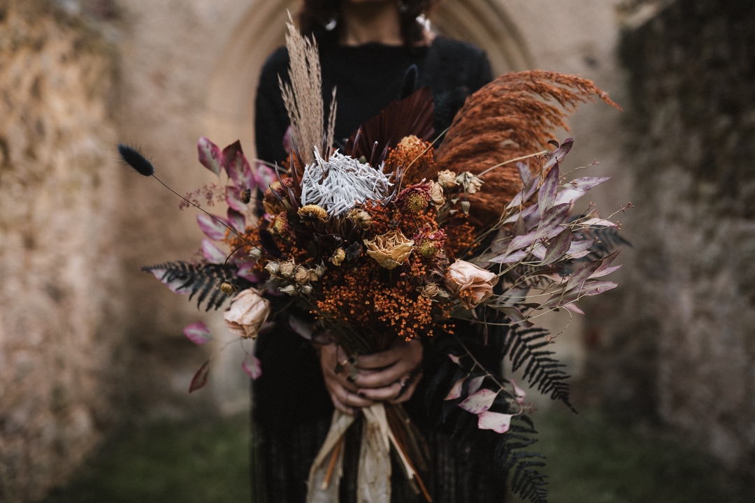 autumn elopement wedding bouquet- dried wedding flowers tied with rustic ribbon held in the brides hands