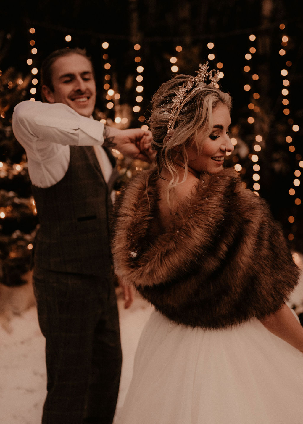 elegant winter wedding -couple dancing in the snow with sparkley fairy lights