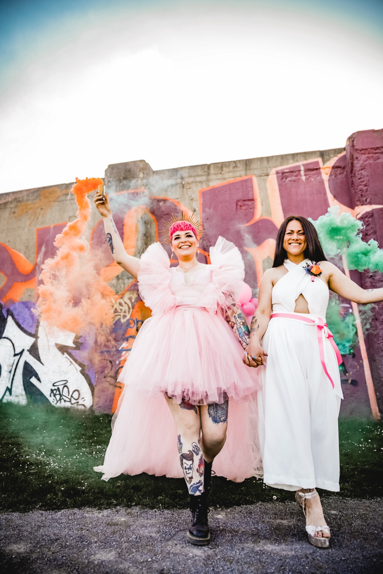two brides with smoke bombs - fun wedding photos - pink wedding dress and unique bridal jumpsuit - same sex wedding inspiration