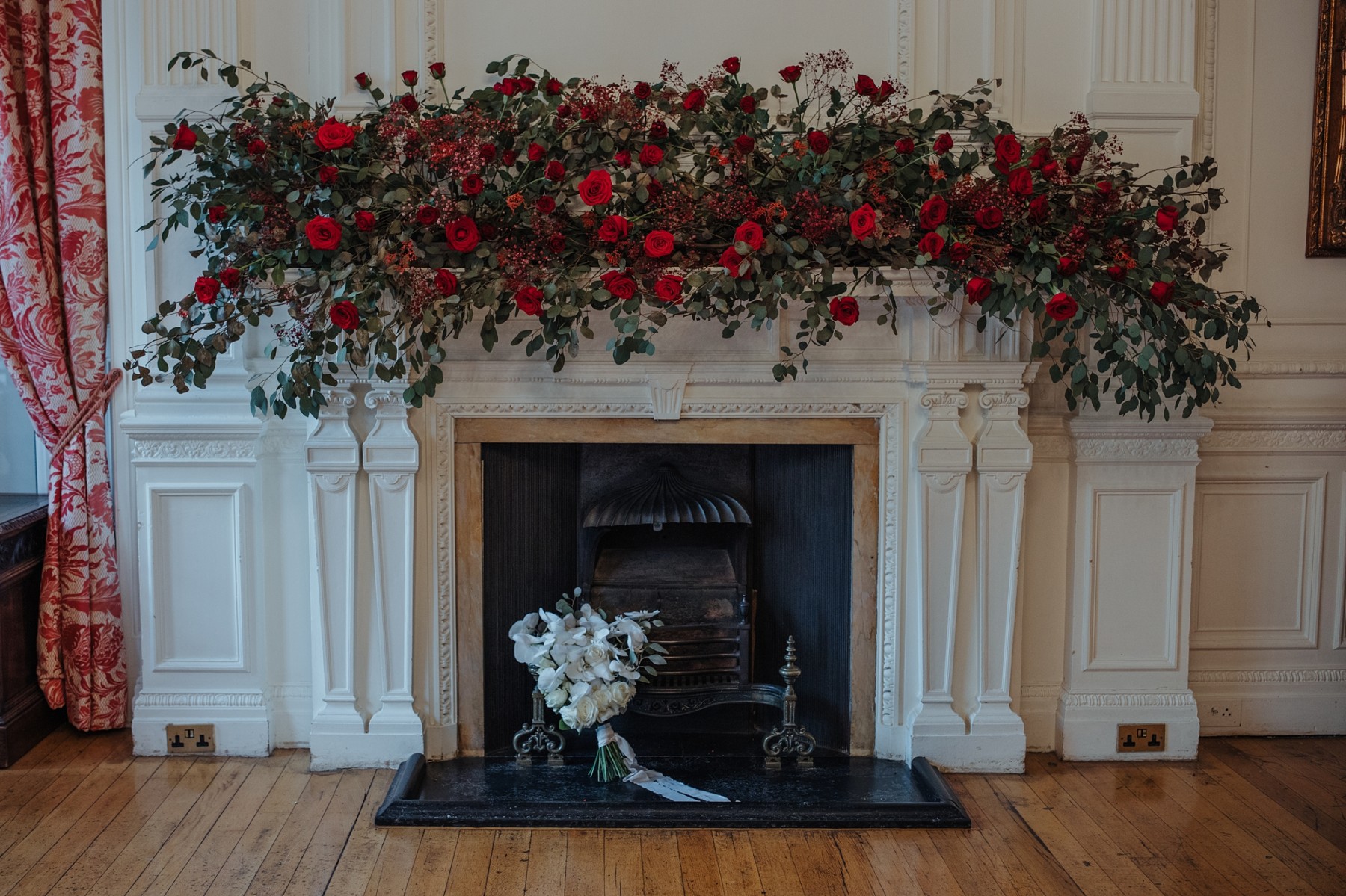 red floral arrangement over white fire place - bold wedding flowers