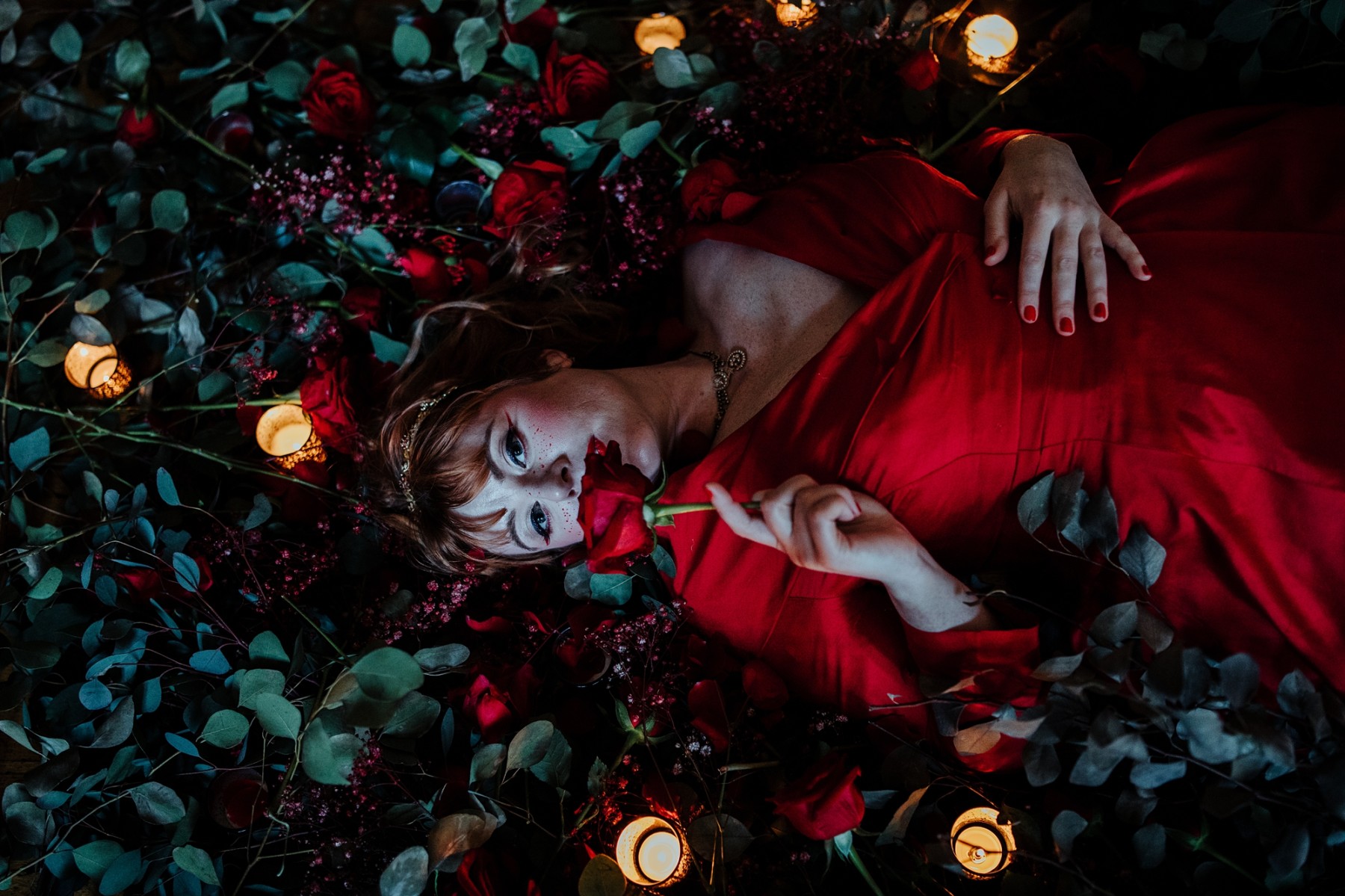 bride in red dress lying in roses - dramatic wedding photos