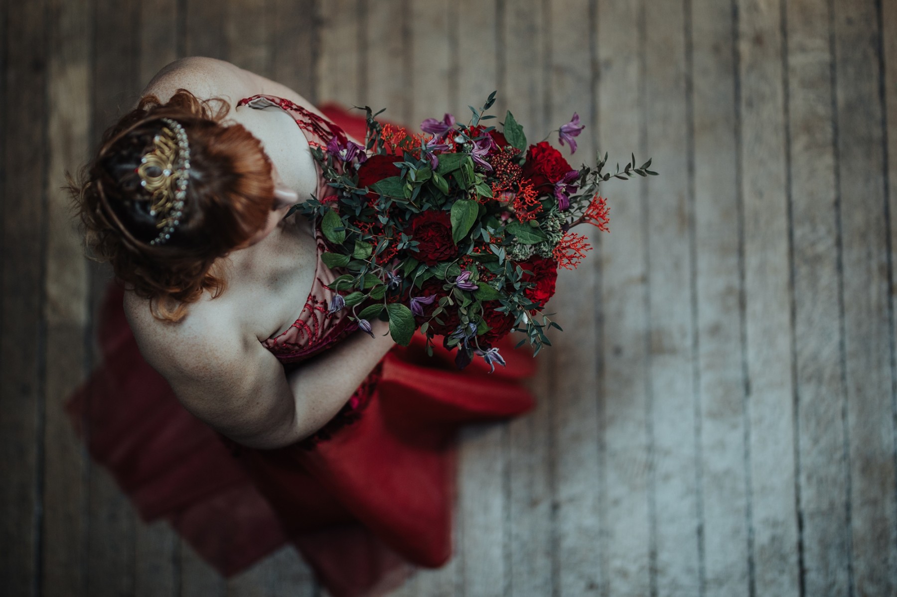 regal wedding - bride wearing red wedding dress and carrying red wedding bouquet
