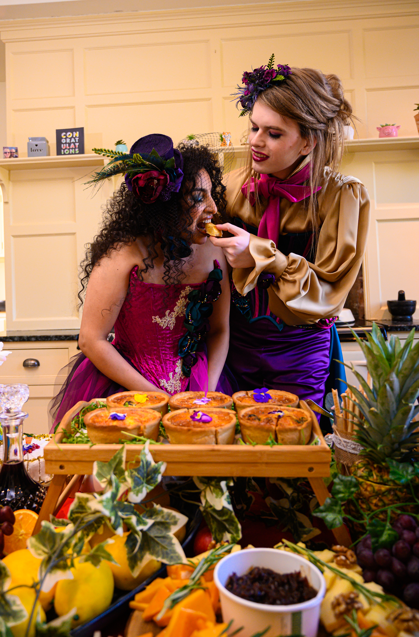 brides feeding each other at a wedding grazing table