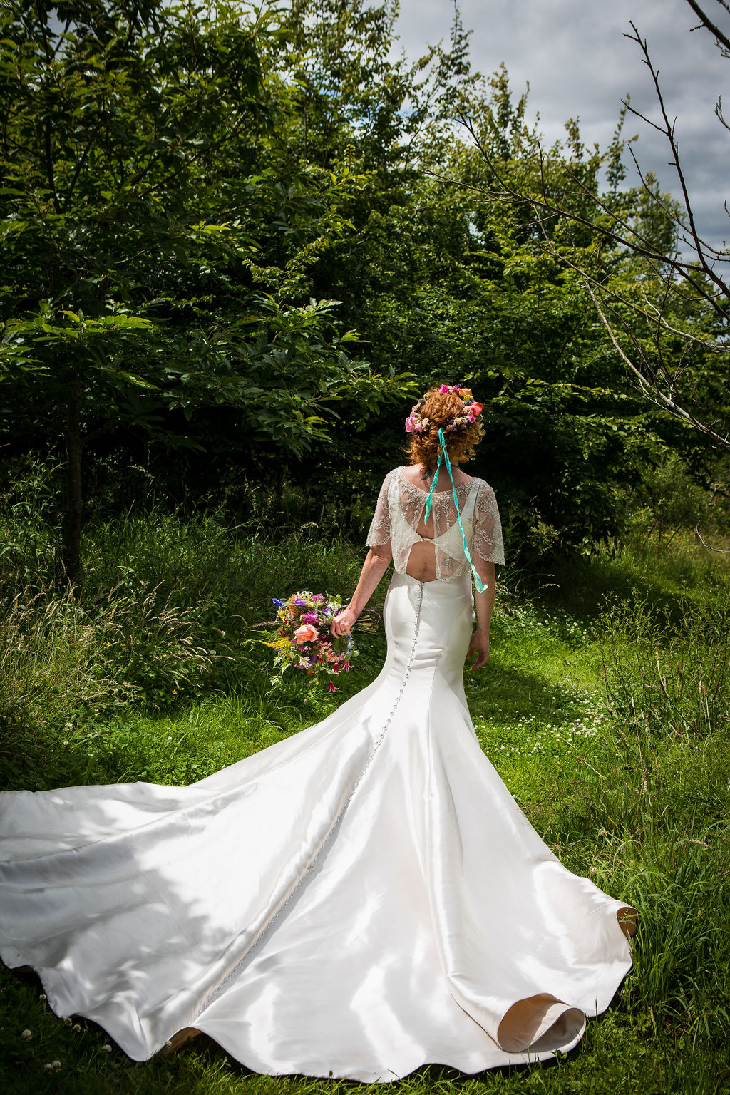 bride with long train in green field - fun boho wedding ideas