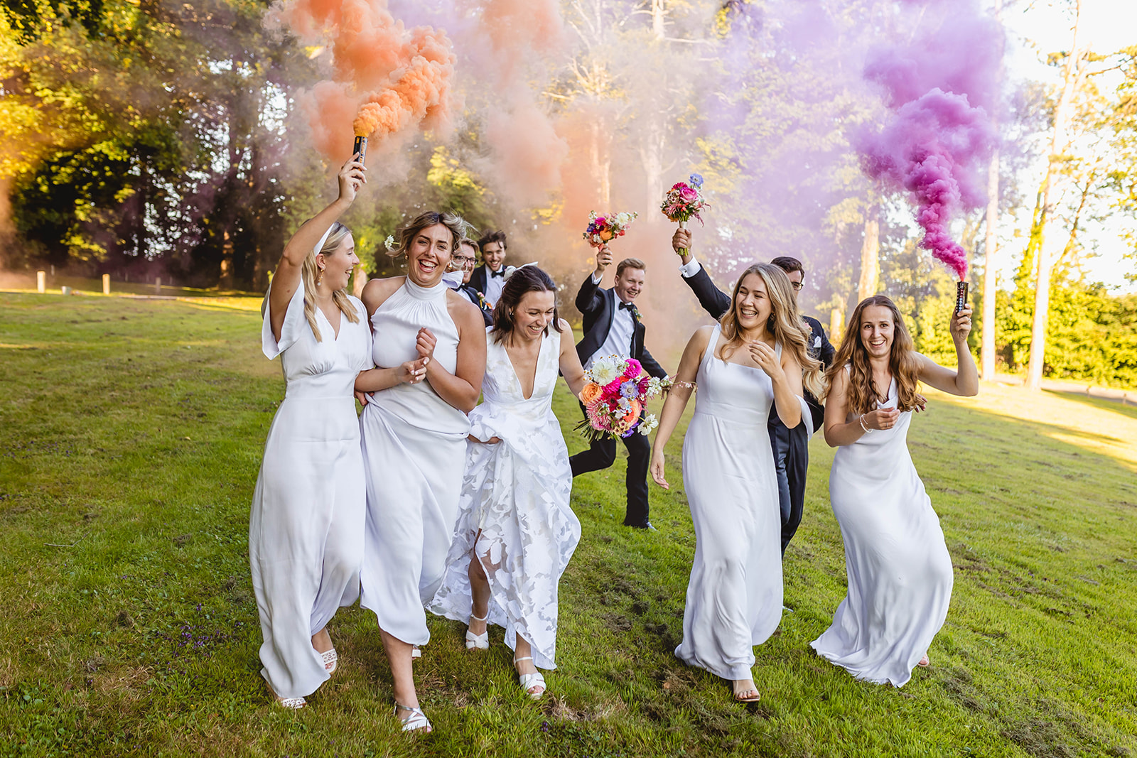 bride and groom have fun with their bridal party running down a hill with coloured smoke cannons. Image taken by carmel mcabe in south wales.