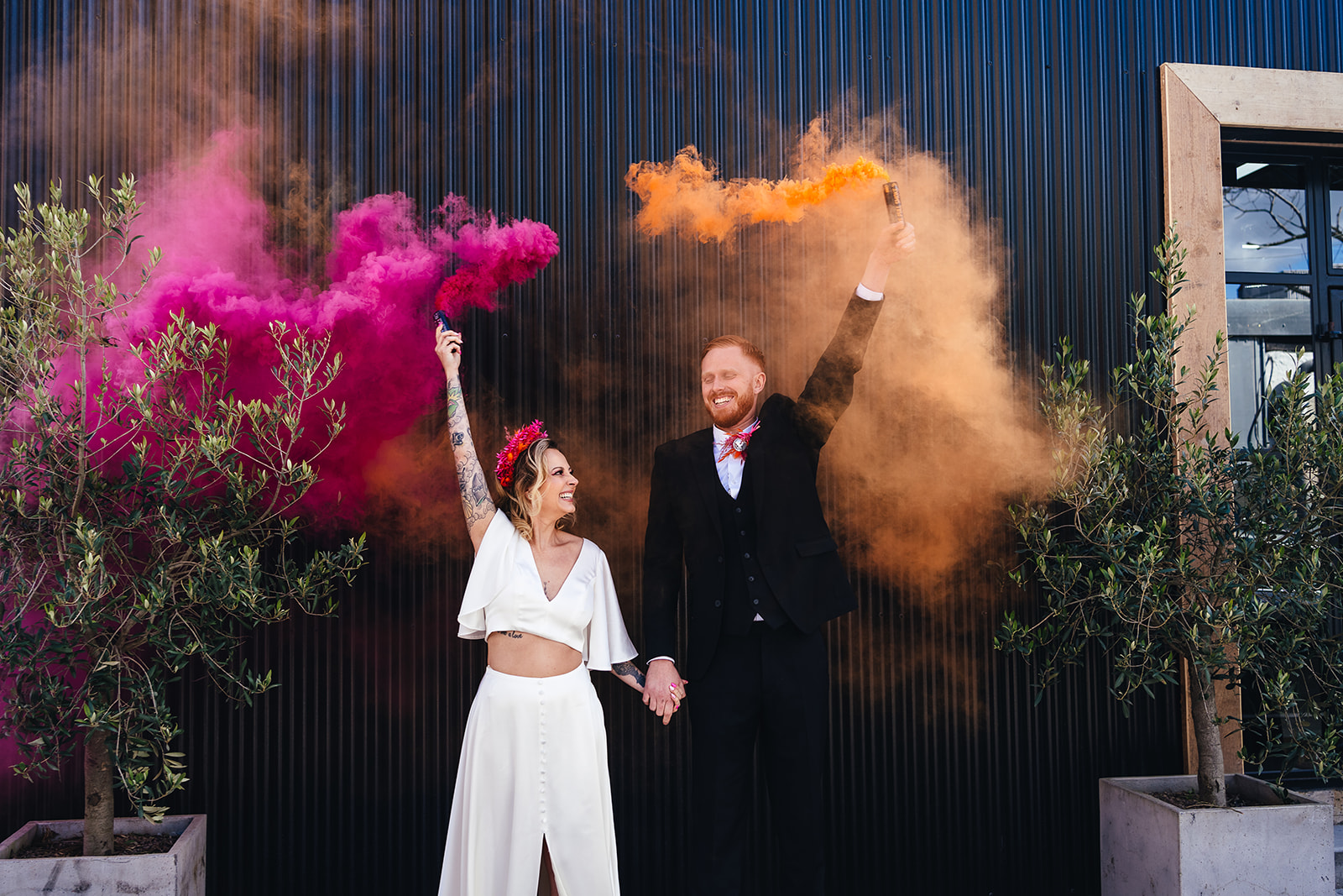 bride and groom holding a smoke bombs in pink and orange - colourful wedding photo ideas