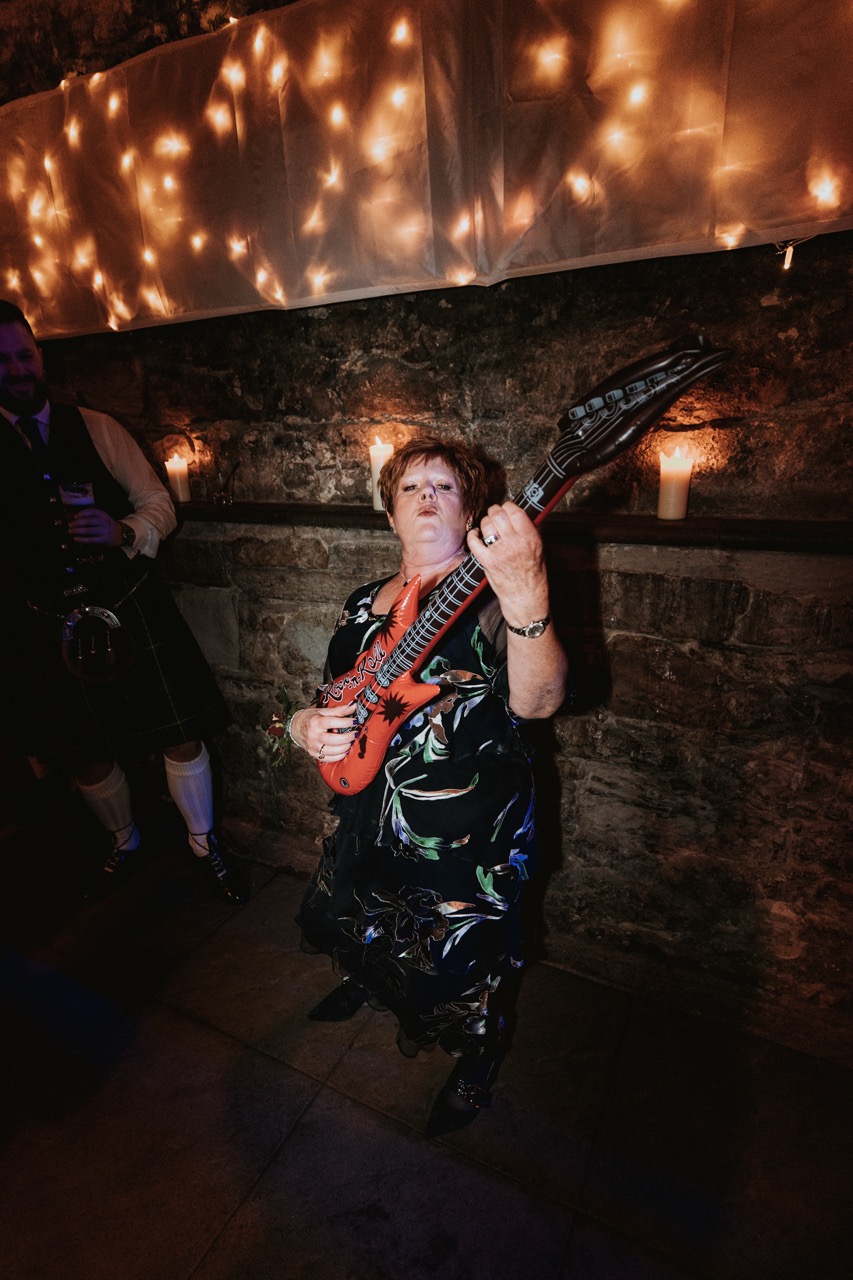 wedding guest dancing with an inflatable guitar - fun dancefloor props for weddings