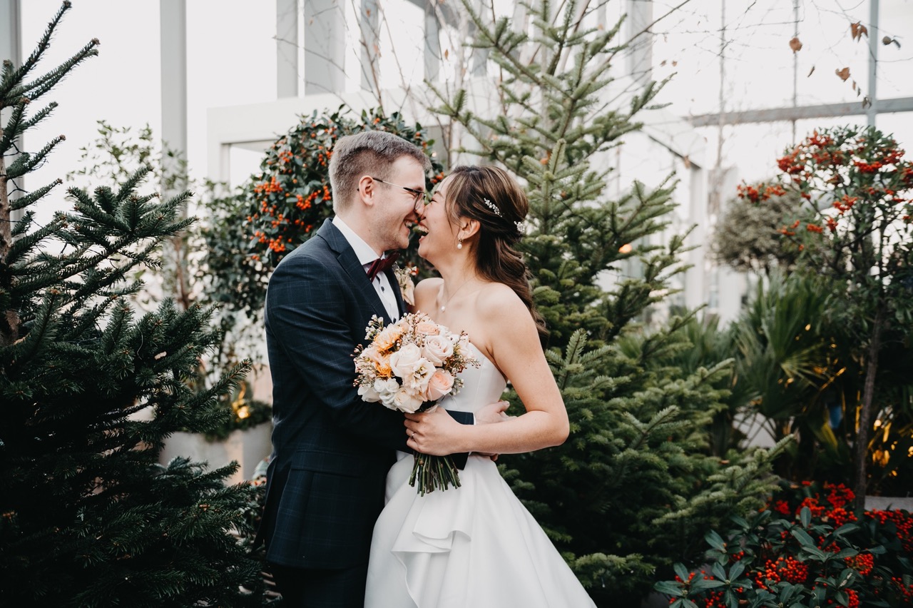 bride and groom smiling in front of christmas trees - city christmas wedding