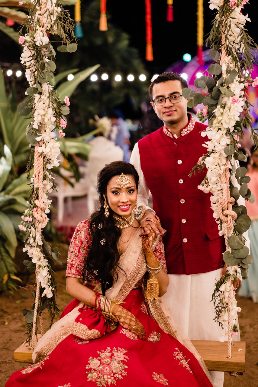 bride sitting on a swing with groom stood behind her - thailand destination wedding