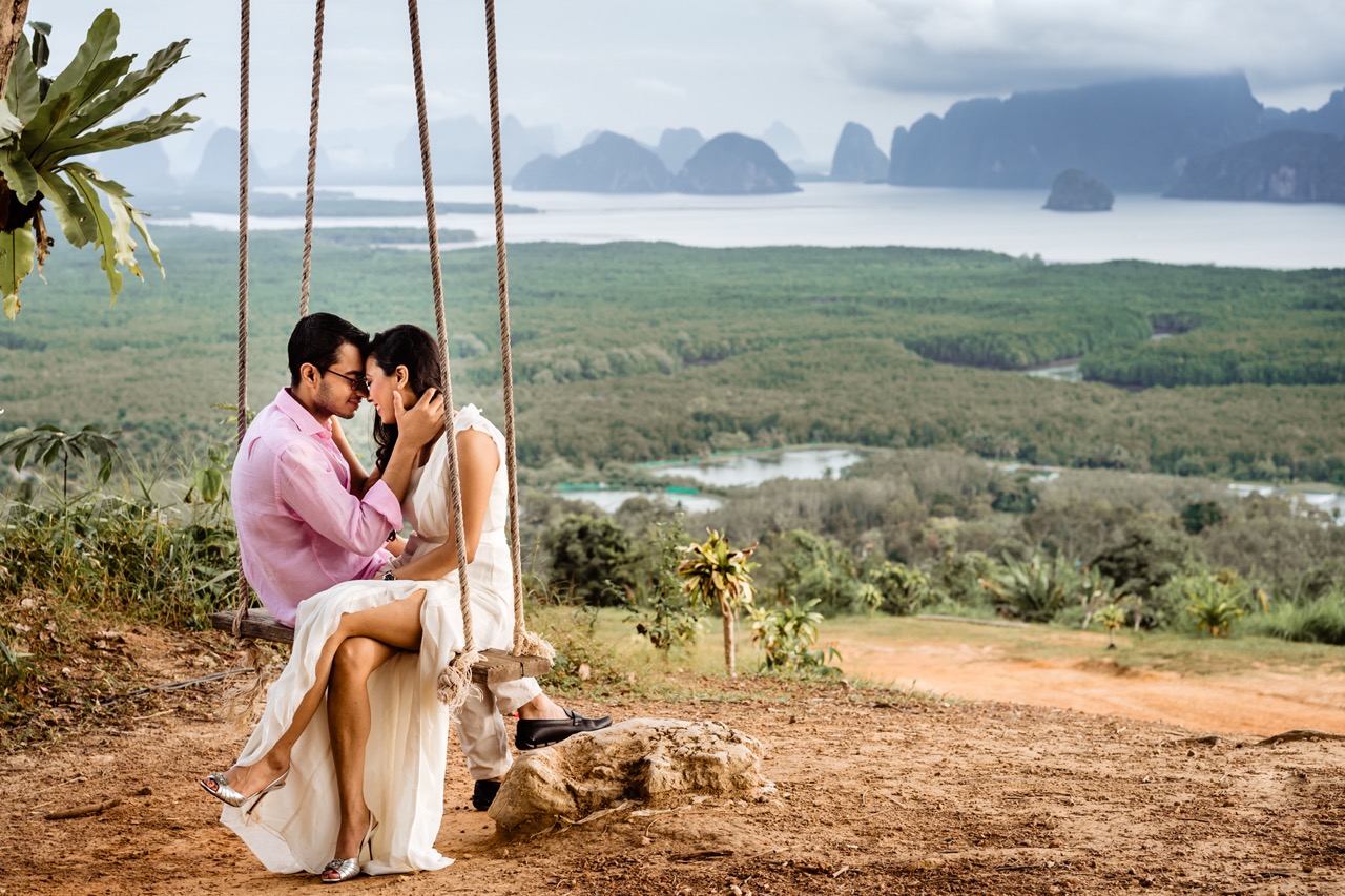 bride and groom sat on a rope swing together after their destination wedding in thailand