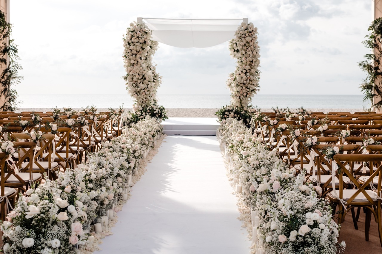 thailand destinaton wedding ceremony set up by the beach with white floral arch