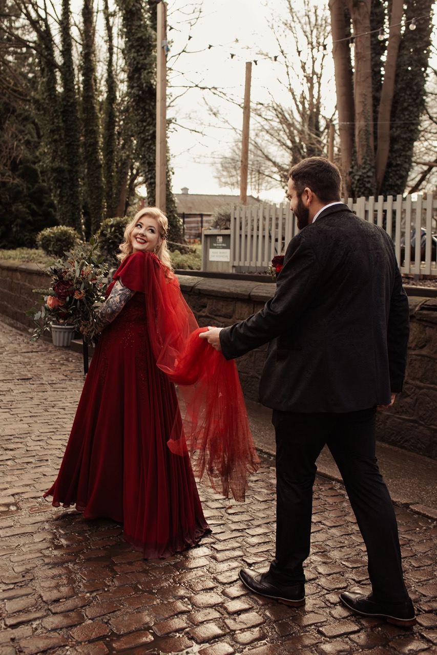 bride wearing red wedding dress with red tulle cape