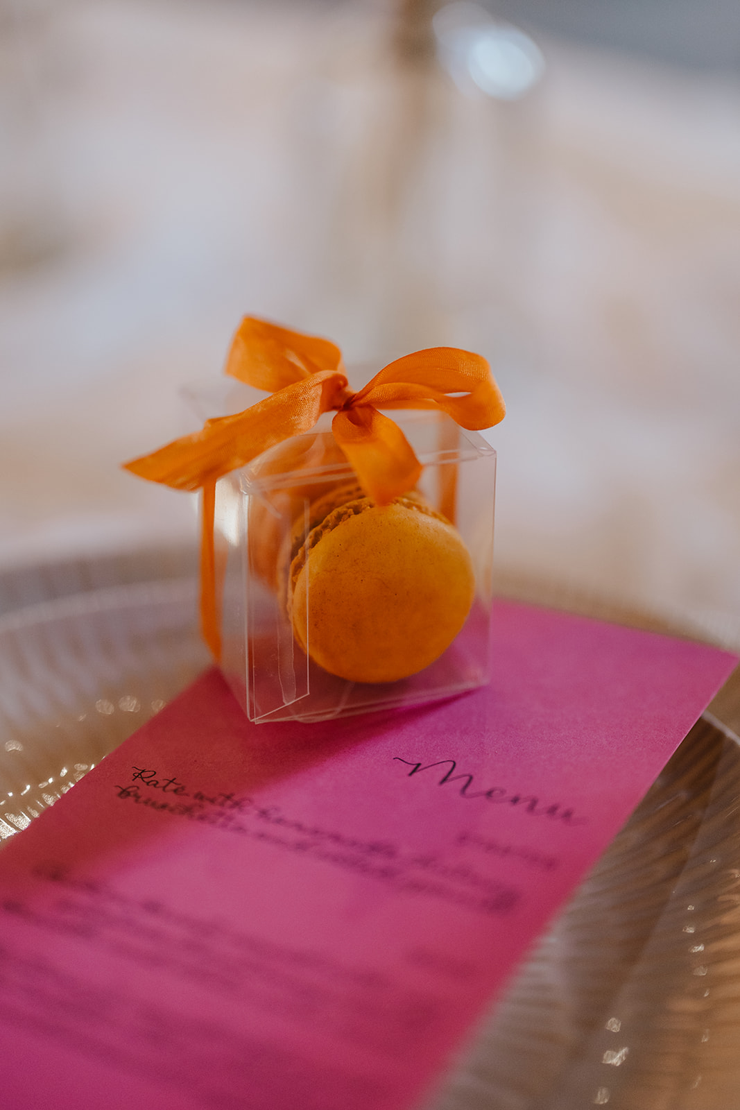 orange macaron wedding favour next to pink menu