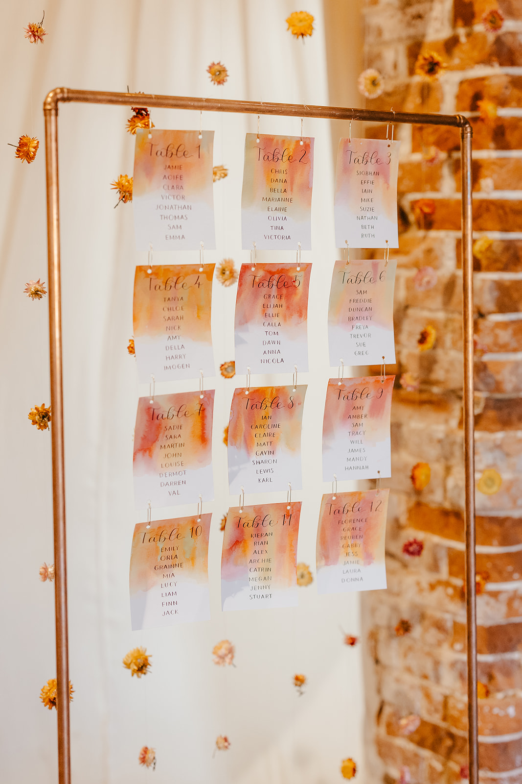 bright spring wedding seating plan against backdrop of dried flowers