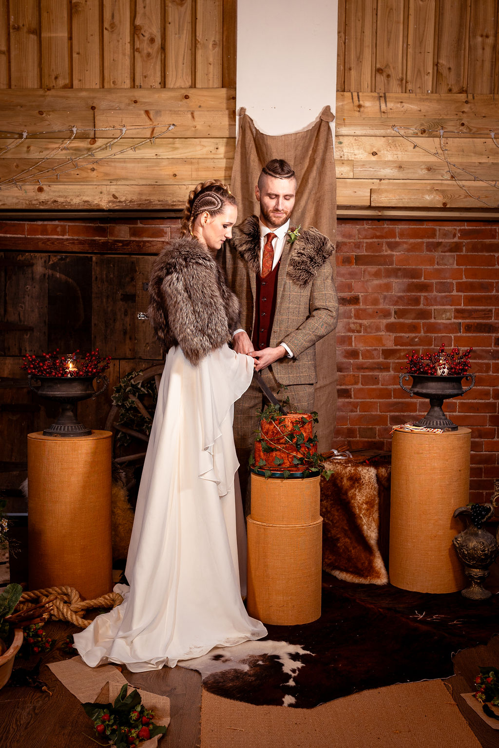viking bride and groom cut the wedding cake that is made to look like a real tree stump
