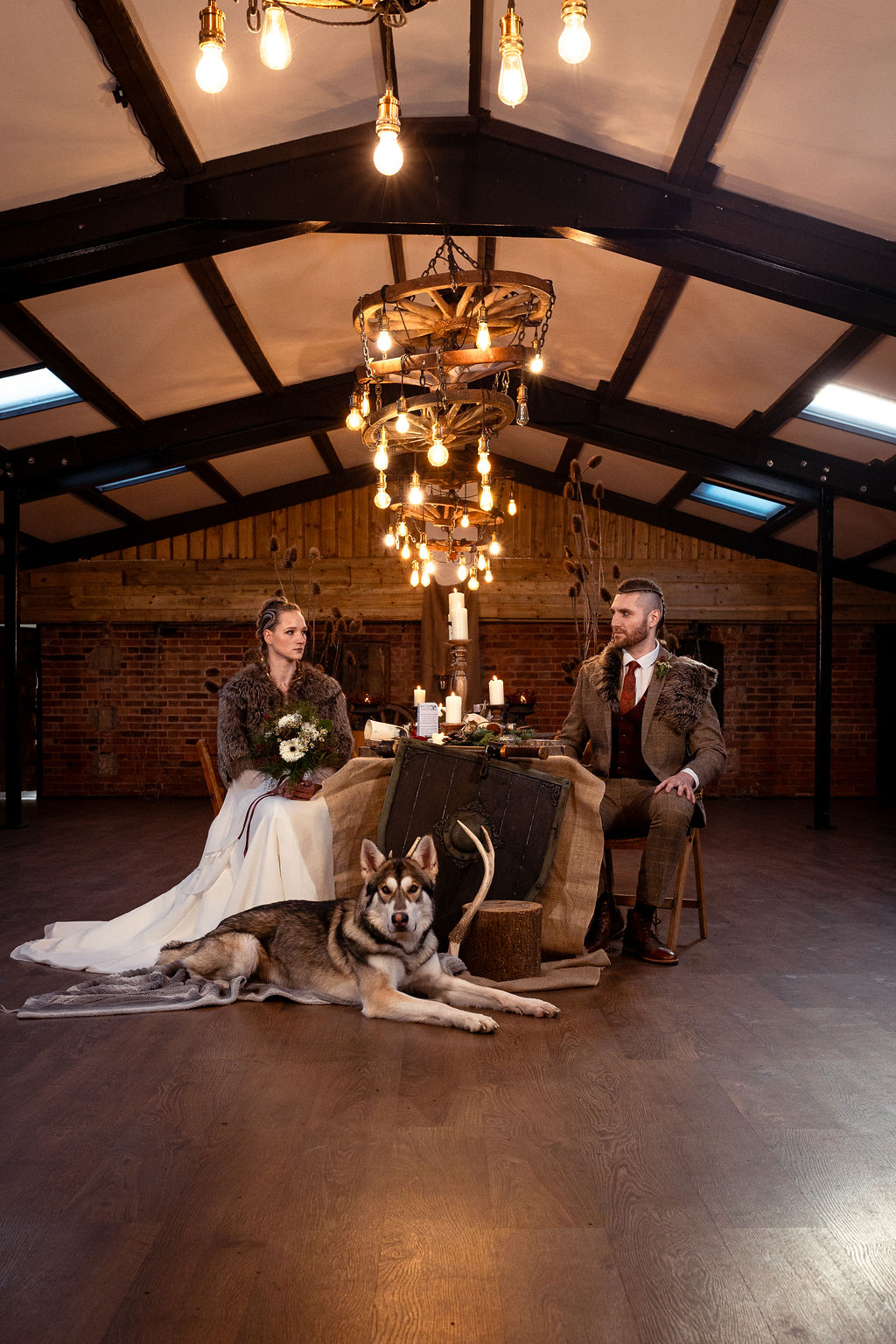 viking bride and groom with their husky dog sit together for a photo