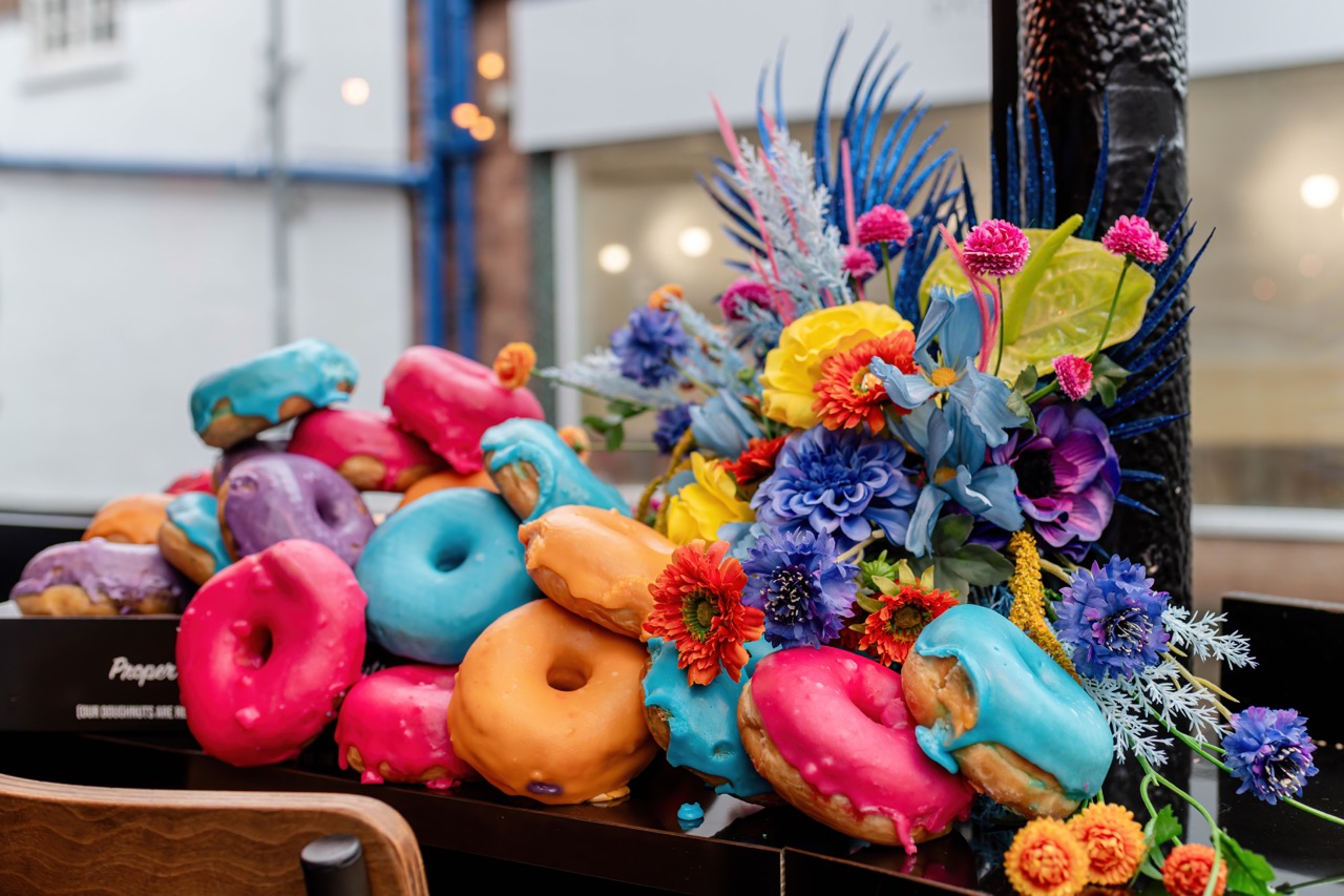 a selection of multicoloured ring doughnuts that match the colour of the bridal bouquet
