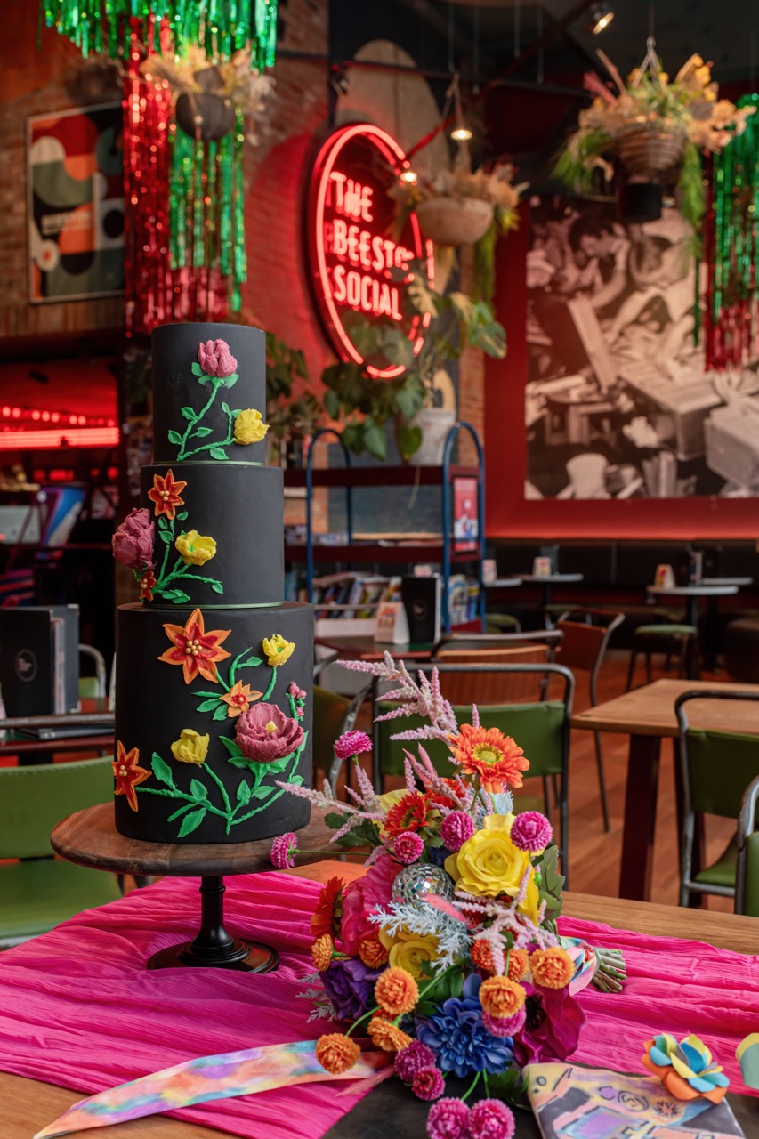 3 tier black iced wedding cake with multicoloured iced flowers match the colours of the bridal bouquet