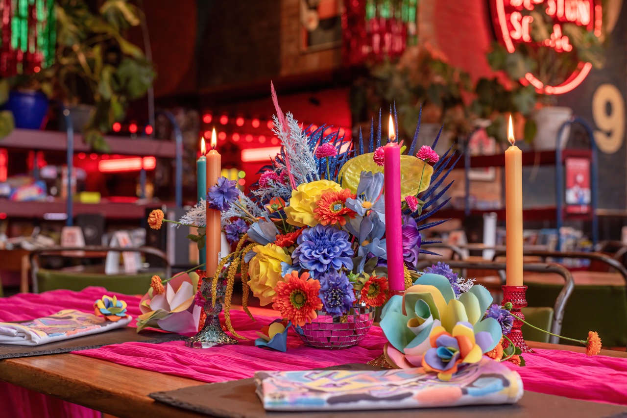 vibrant table decor with multicoloured flowers and tapered candles