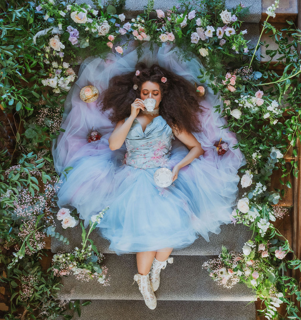 bride in blue tulle wedding dress lying amongst pastel wedding flowers