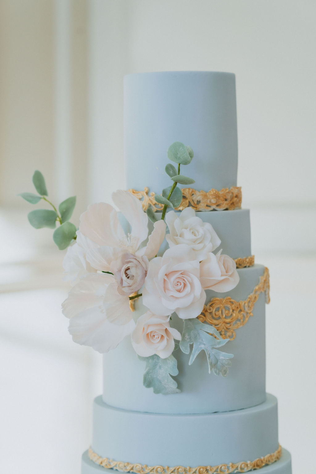 gold and light blue wedding cake with floral decoration