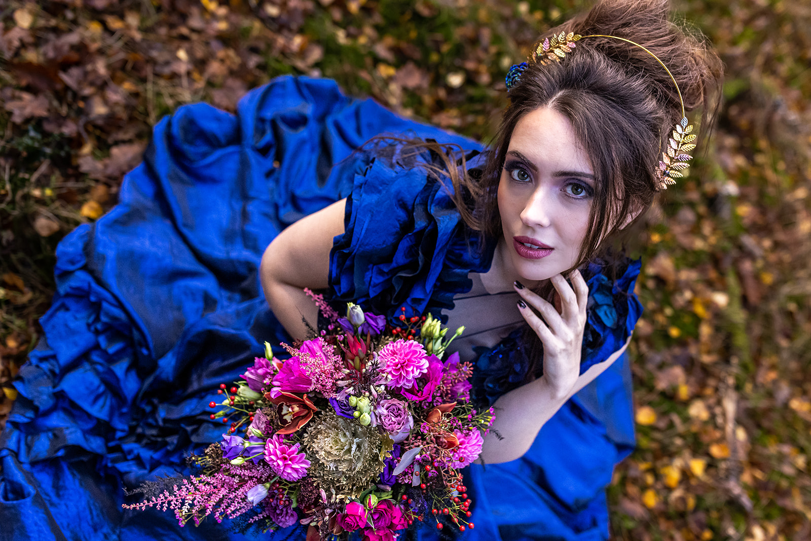 bride wearing electric blue wedding dress designed by caroline versallion in an outdoor woodland wedding ceremony shoot