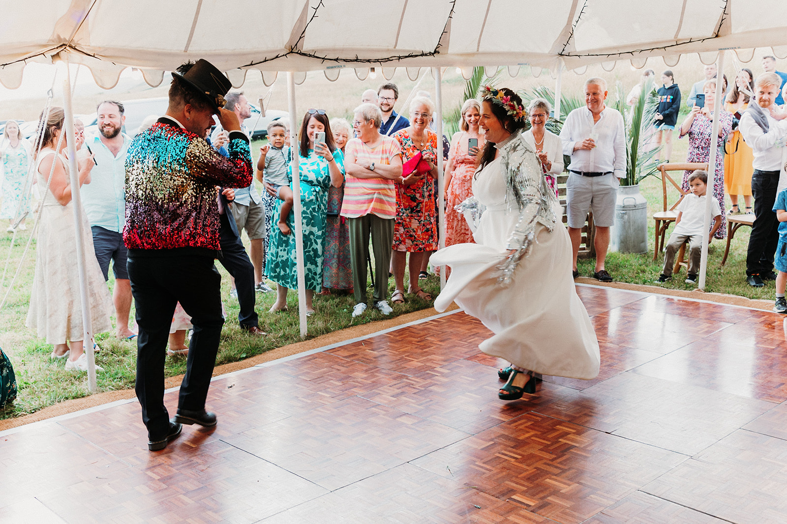 bride and groom first dance in marquee wedding. bride and groom wear colourful sequin wedding jackets