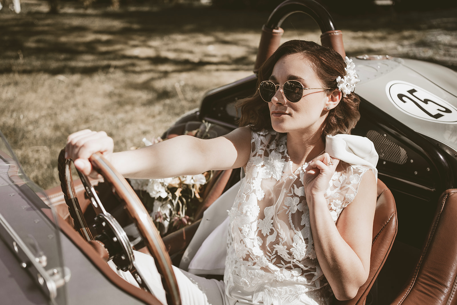 bride sitting in vintage car at outdoor wedding