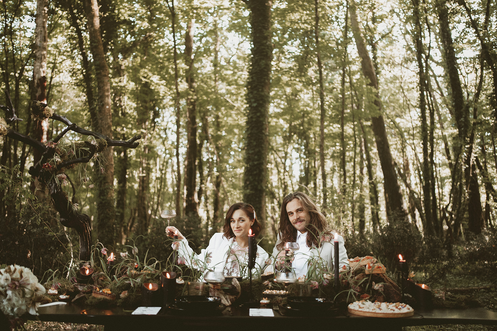 bride and groom sitting at wedding table in unique forest wedding