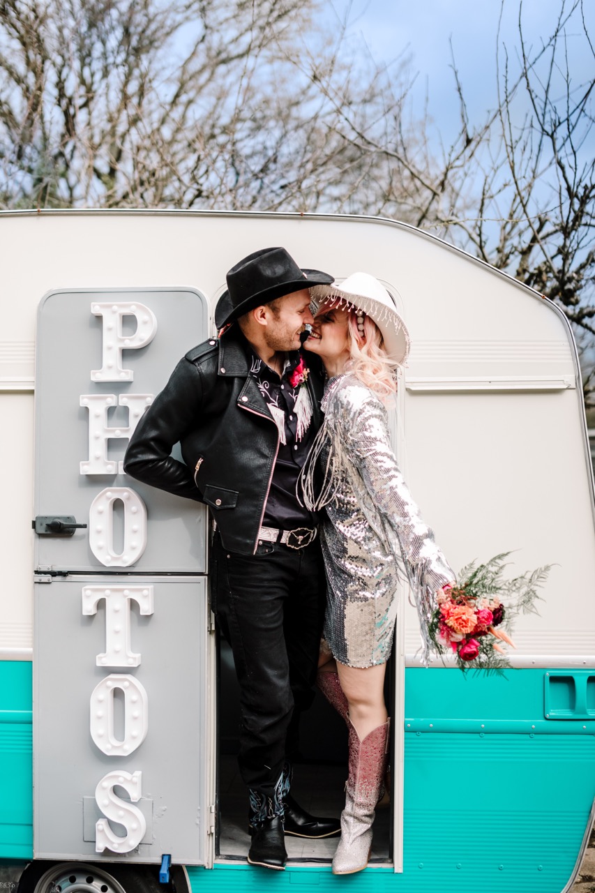 bride and groom in cowboy hats posing in photo boooth