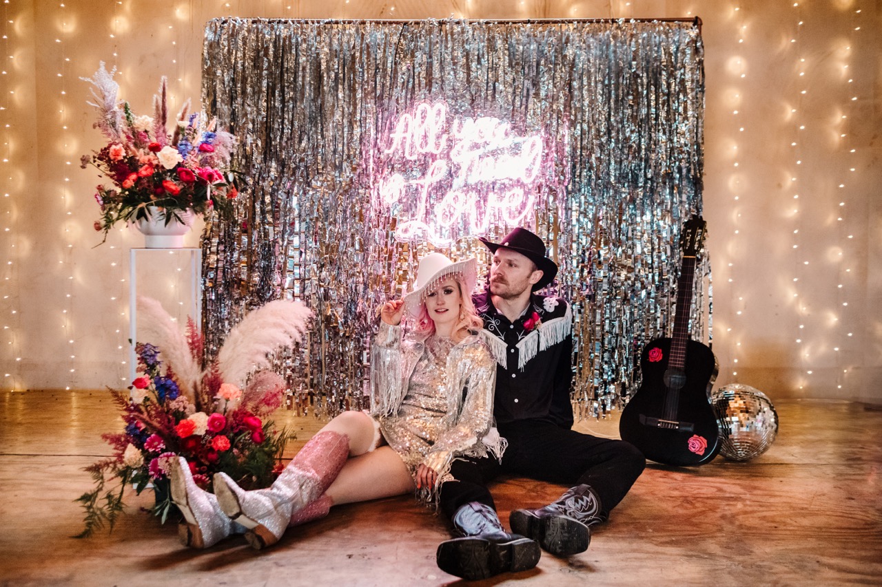 silver tassel wedding backdrop with neon pink signage