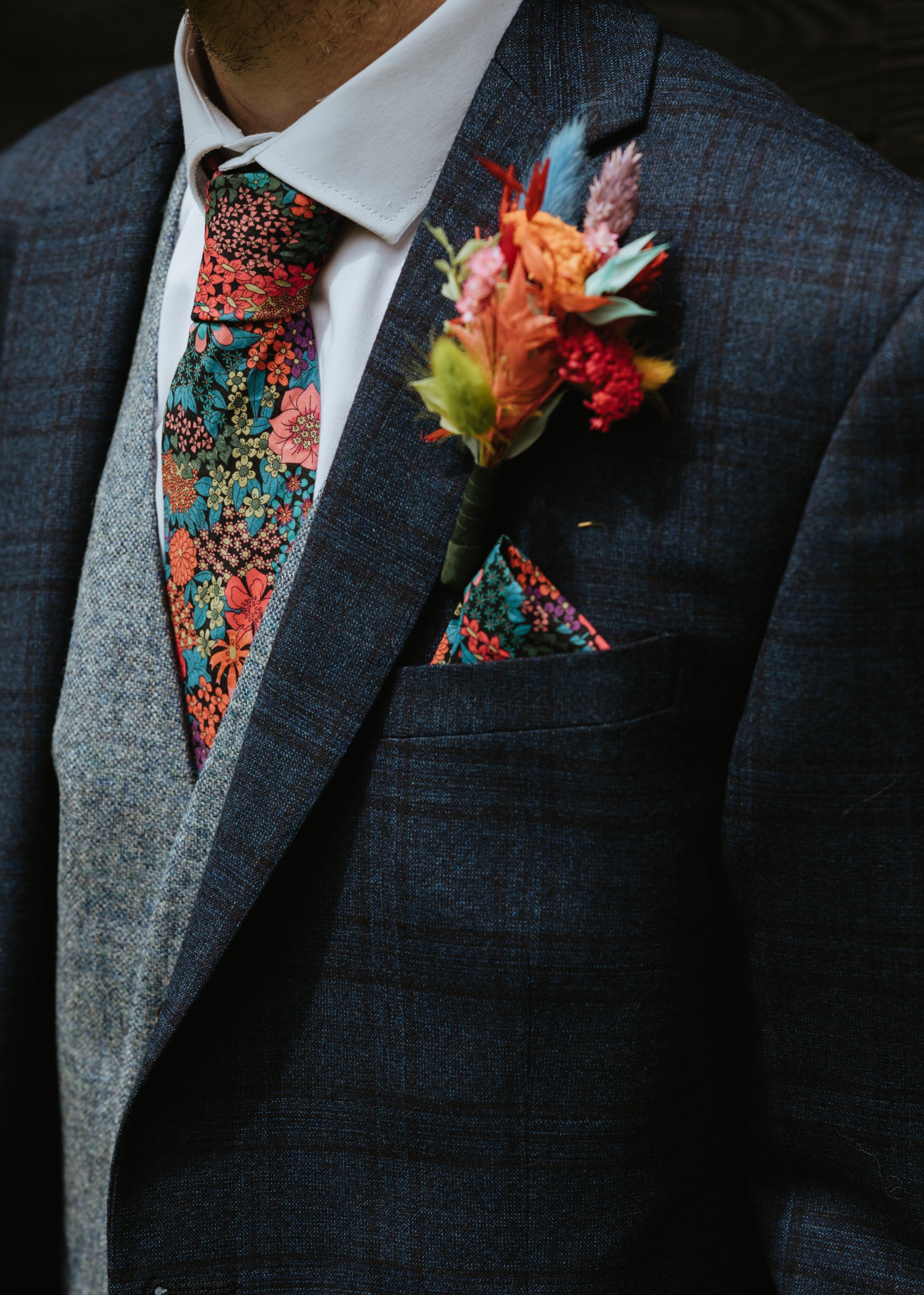 groom wearing navy suit with colourful tie and pocket square
