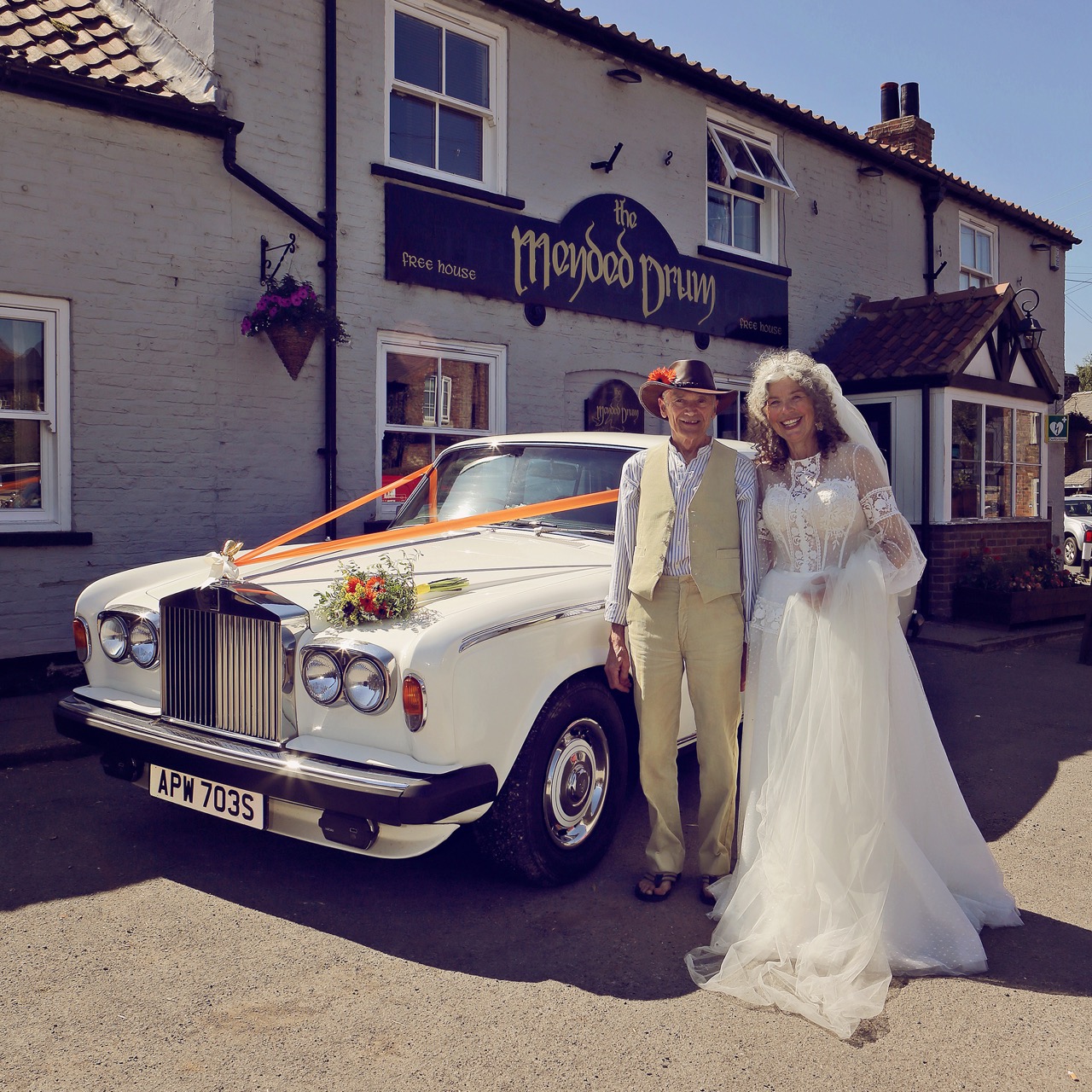 mature bride and groom standing outside of a pub with a vintage wedding car - small summer wedding inspiration