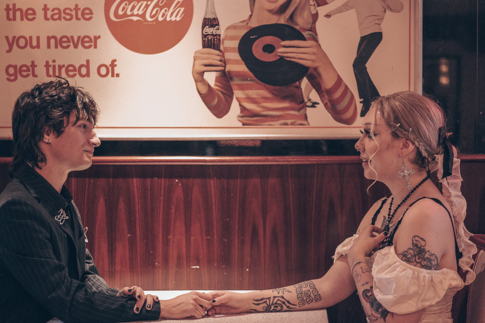 gothic rock bride and groom sit together in a bar holding hands