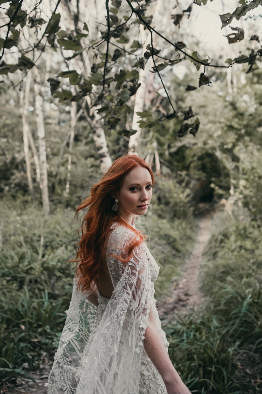 red headed bride in a forest wearing a wedding dress with a cape - unique wedding dress