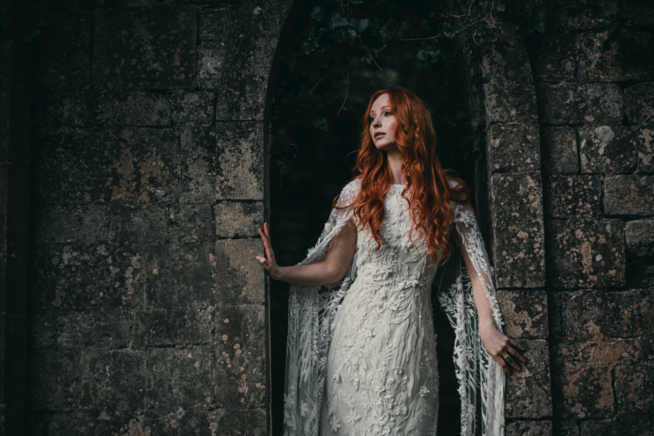 bride in the ruins of a woodland castle, wearing an embroidered wedding dress
