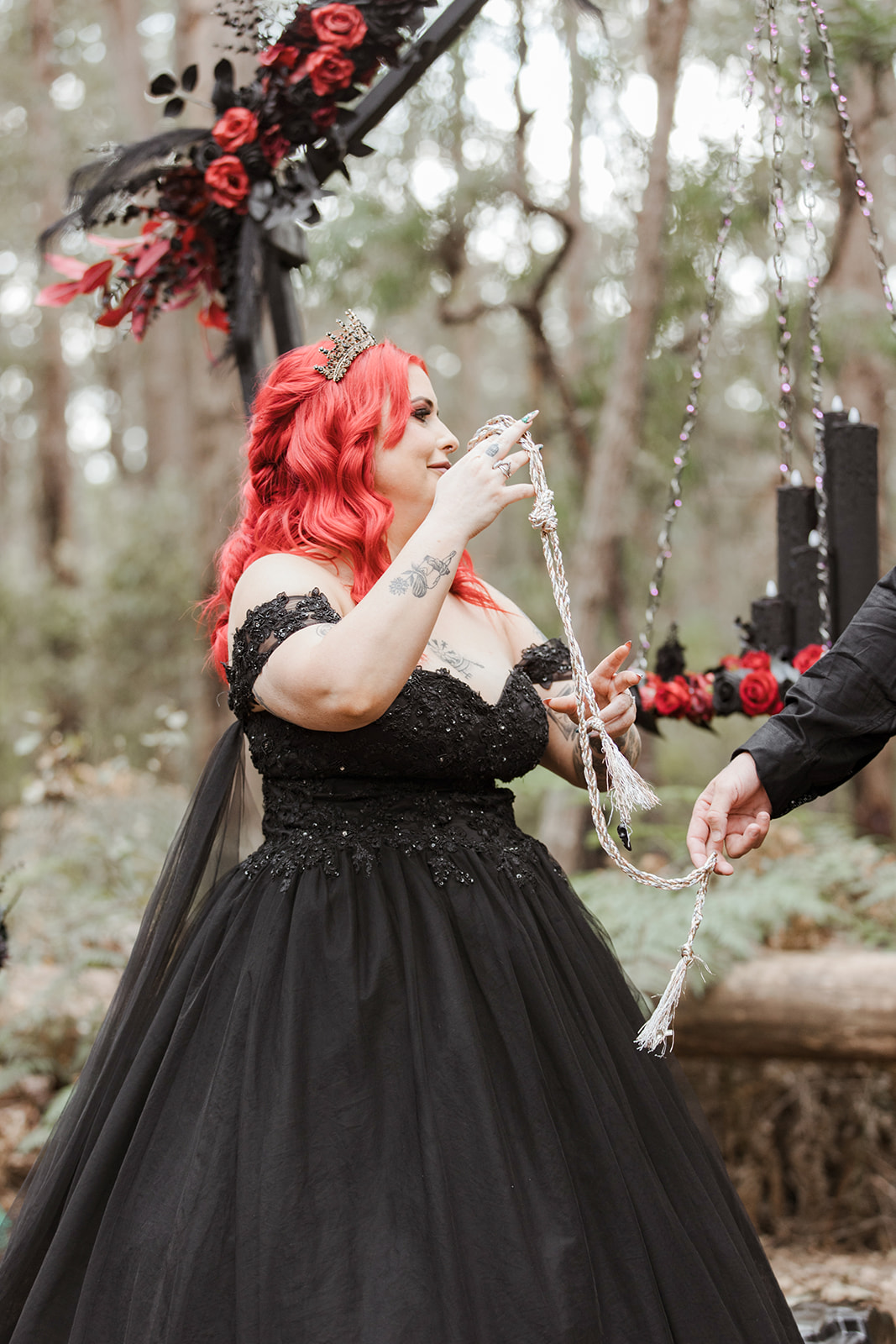 handfasting ceremony at gothic pagan wedding - bride has red hair and a black wedding dress