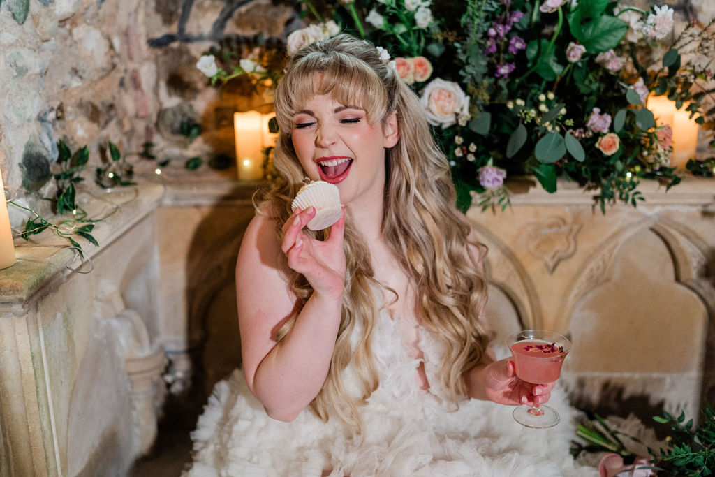 bride smiling and eating a cupcake at sleeping beauty themed wedding