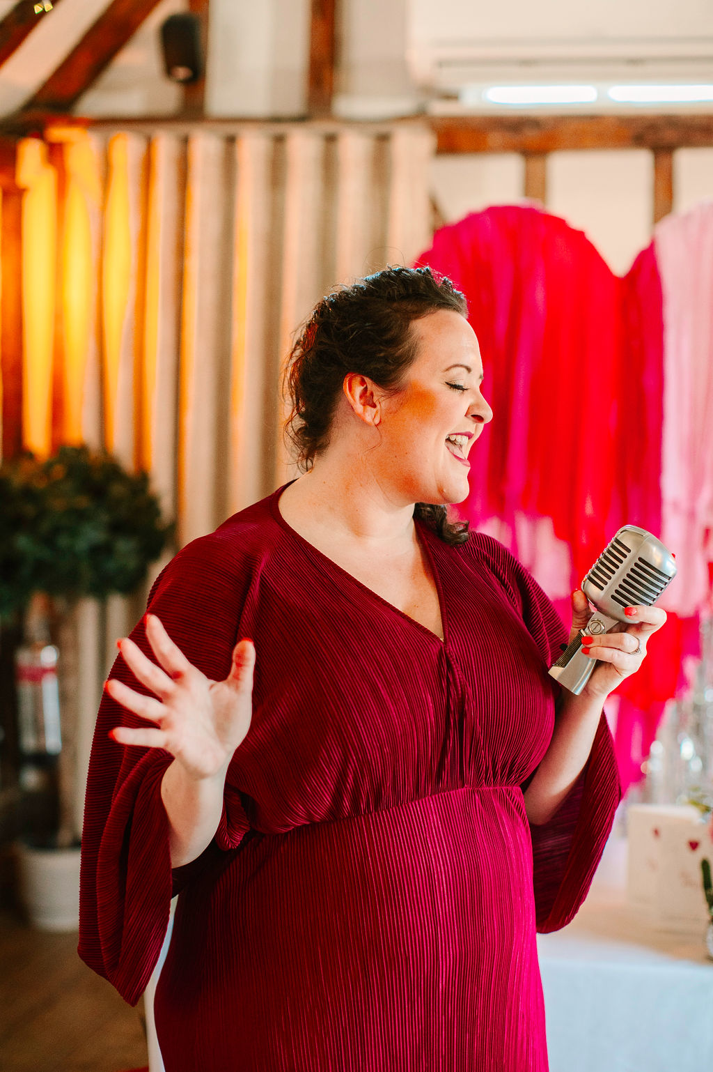 Wedding singer performing in front of pink and red love heart backdrop as part of fun wedding