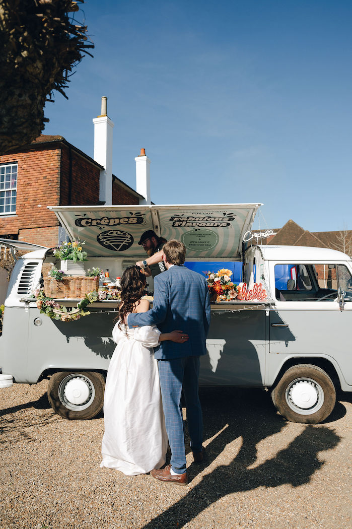 Couple stood at crepe van getting handmade wedding day crepes