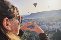 wedding celebrant, stardust ceremonies, is stood on a mountain top watching hot hair balloons at a destination wedding